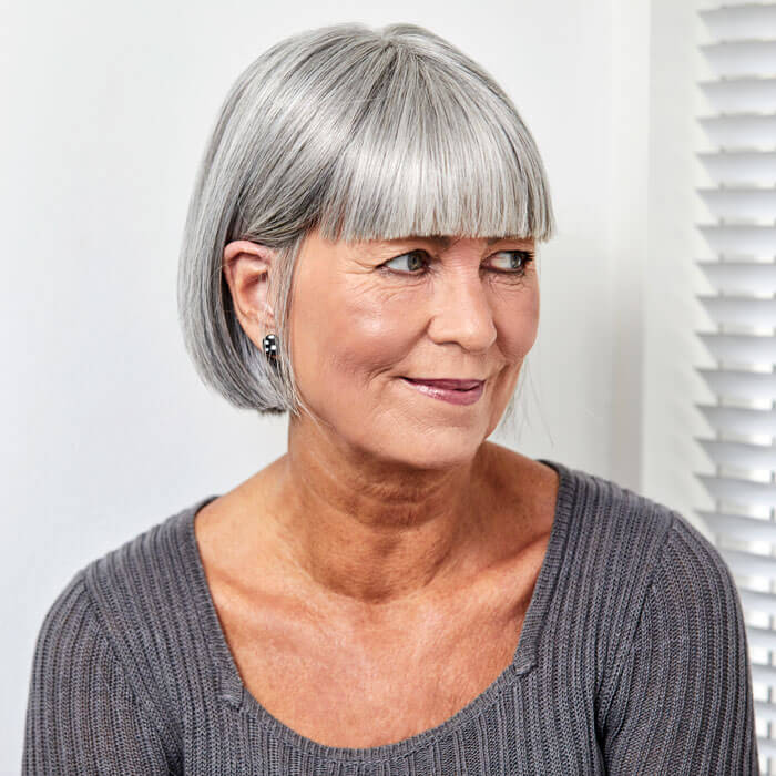 Kvinde med smuk grå paryk, der har page frisure og pandehår