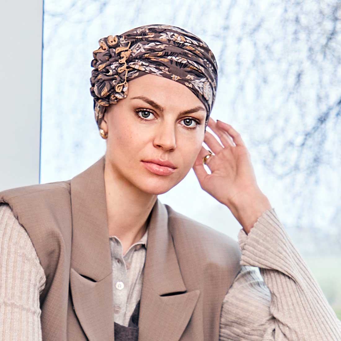 Lotus turban i brun med et blomstret mønster i hvide, gule og sorte farver.